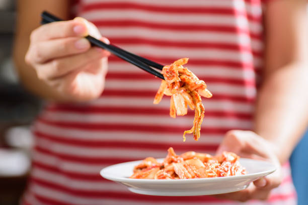 Korean food, kimchi cabbage on white dish holding by hand with chopsticks for eating.Healthy food