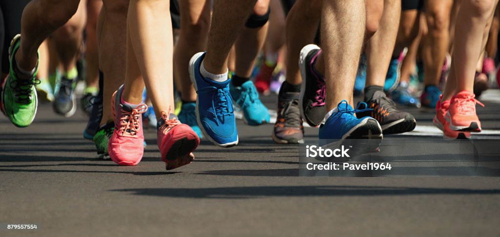 Marathon runners running on city road Marathon runners running on city road,detail on legs Running Stock Photo