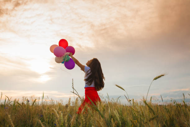 istock Girl with balloons in wheat field 879562068