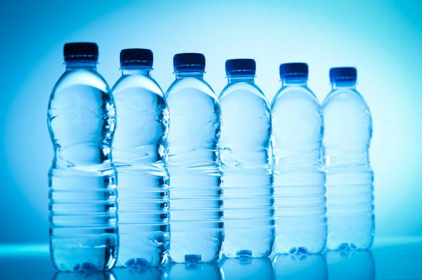 garrafas de plástico de água isolado azul - water bottle purified water water drink - fotografias e filmes do acervo