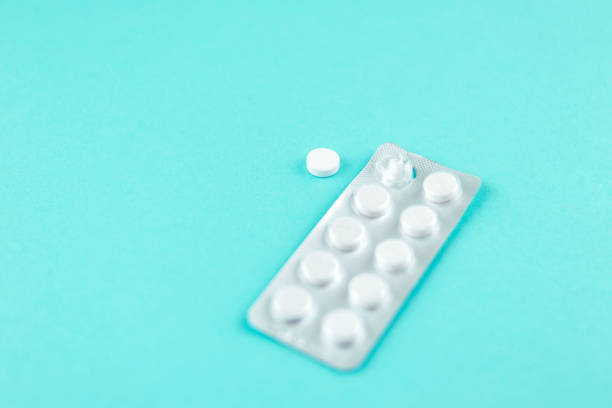 istock Packs of white pills packed in blisters with copy space on turquoise background. Focus on foreground, soft bokeh. Pharmacy drugstore concept 879570854