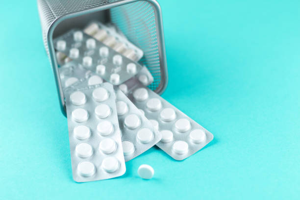 istock Trash bin with packs of white capsules and pills packed in blisters with copy space on turquoise background. Focus on foreground, soft bokeh. Pharmacy drugstore concept 879571092