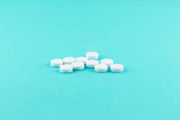 istock White pills with copy space on turquoise background. Focus on foreground, soft bokeh. Pharmacy drugstore concept 879573296