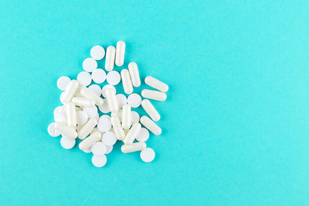 istock Close up white pills and capsules on turquoise background with copy space. Focus on foreground, soft bokeh. Pharmacy drugstore concept. Top view 879576634