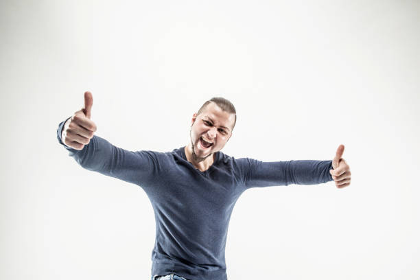 smiling athletic guy bodybuilder in jeans and t-shirt showing thumbs up gesture. the photo has a empty space for your text