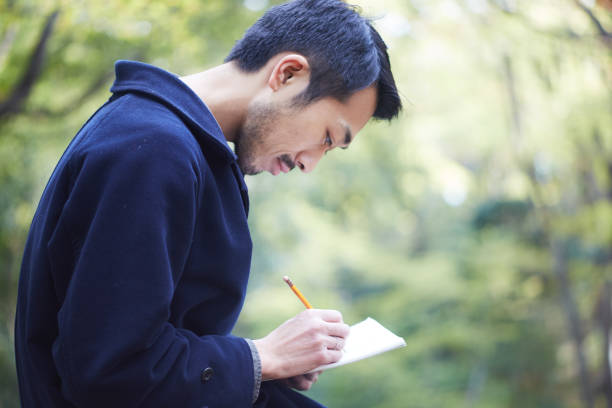 young man sketching in the woods lit with sunshine