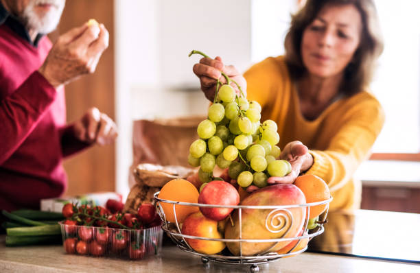 senior couple preparing food in the kitchen. - cooking senior adult healthy lifestyle couple imagens e fotografias de stock