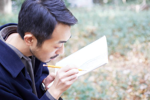 young man sketching in the woods lit with sunshine