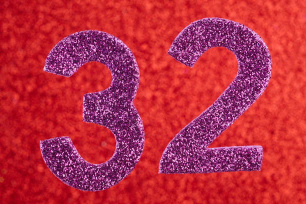 istock Number thirty-two purple color over a red background. Anniversary 879597822