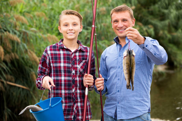 istock Man with teenager boy showing catch fish 879608908