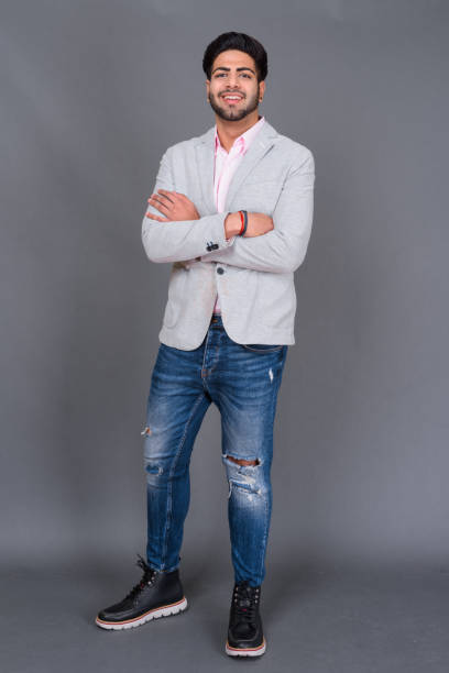 istock Young bearded handsome Indian businessman against gray background 879609120