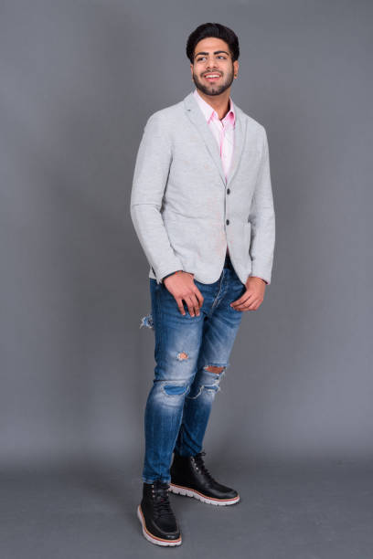 istock Young bearded handsome Indian businessman against gray background 879609156