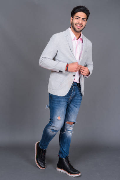 istock Young bearded handsome Indian businessman against gray background 879609158