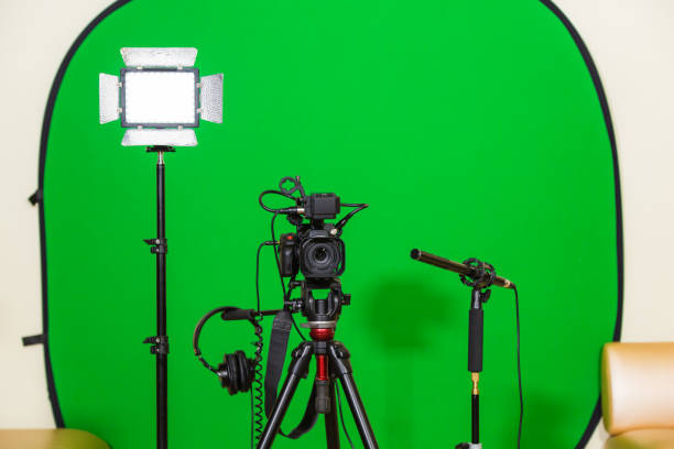istock The camera on the tripod, led floodlight, headphones and a directional microphone on a green background. The chroma key. Green screen 879609350