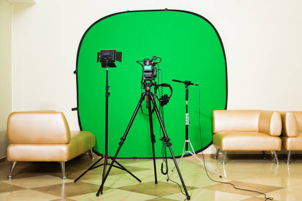 istock The camera on the tripod, led floodlight, headphones and a directional microphone on a green background. The chroma key. Green screen 879609354
