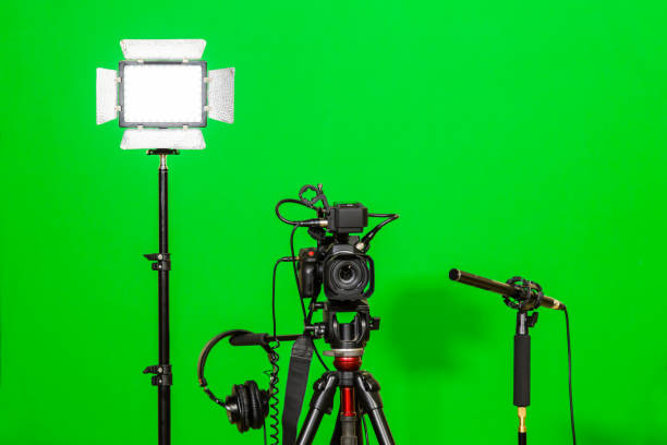 istock The camera on the tripod, led floodlight, headphones and a directional microphone on a green background. The chroma key. Green screen 879609378
