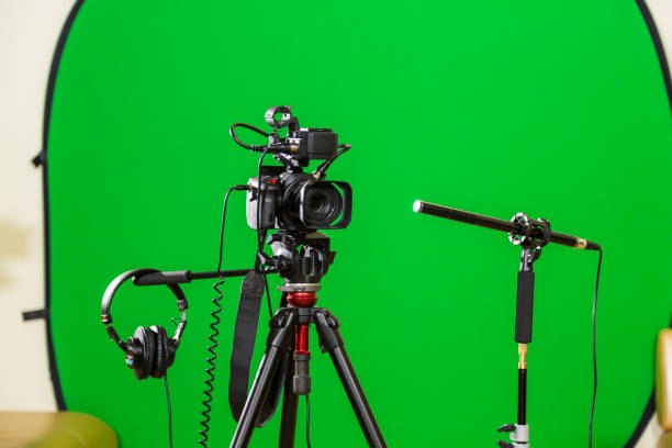 istock Video camera on a tripod, headphones and a directional microphone on a green background. The chroma key 879609396