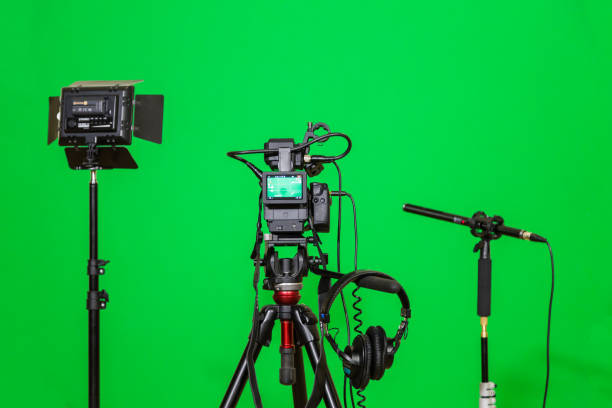 istock The camera on the tripod, led floodlight, headphones and a directional microphone on a green background. The chroma key. Green screen 879609422