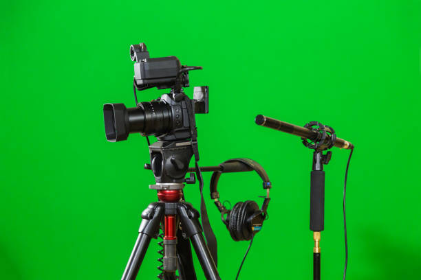 istock Video camera on a tripod, headphones and a directional microphone on a green background. The chroma key 879609426