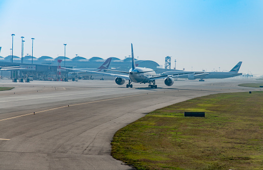 Looking at aircraft standing at the runway at Hong Kong International Airport during the day.