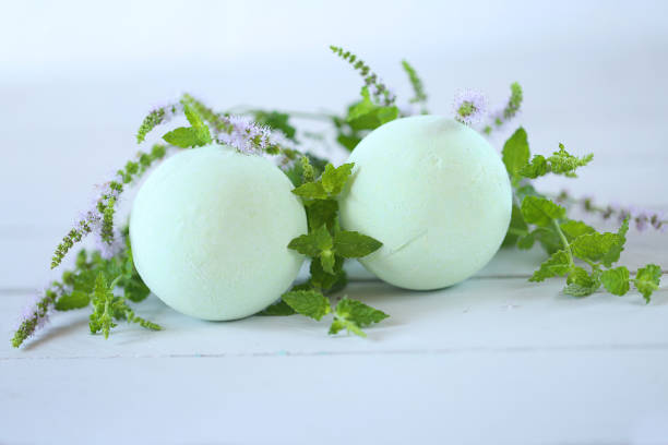 istock Mint bath bomb. two green bath bombs with mint extract and twigs of flowering mint on a light gray wooden backgroun 879637056