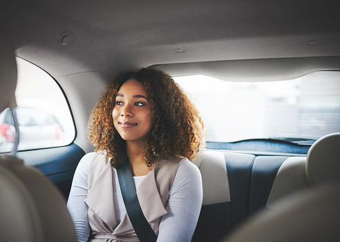 Cropped shot of an attractive young woman sitting in the backseat of a car