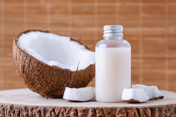 bottiglia cosmetica e cocco biologico fresco per la cura della pelle, sfondo naturale - latte di cocco foto e immagini stock