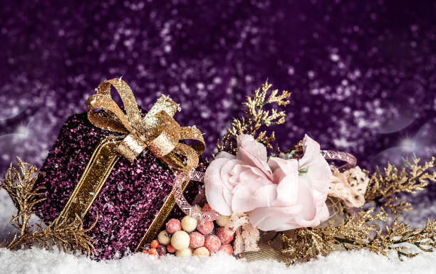 istock purple shiny gift with a gold bow, on a snowy background 879644286