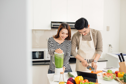 Portrait of happy asian young couple cooking together in the kitchen at home.