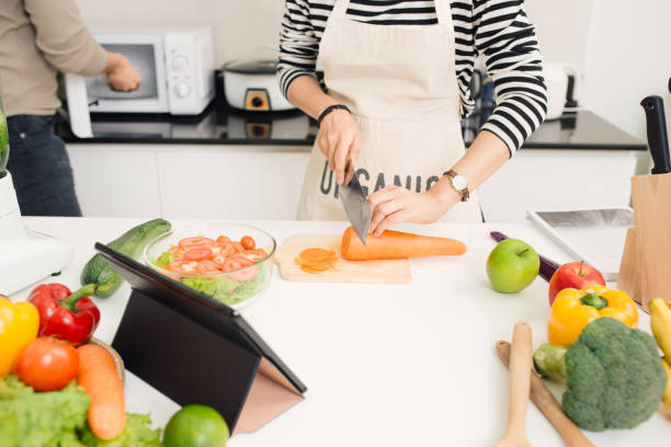 istock Young woman cutting vegetables in the kitchen. 879645074