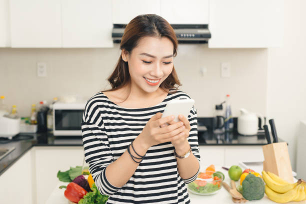 istock Smiling asian woman in the kitchen writing text message 879651236