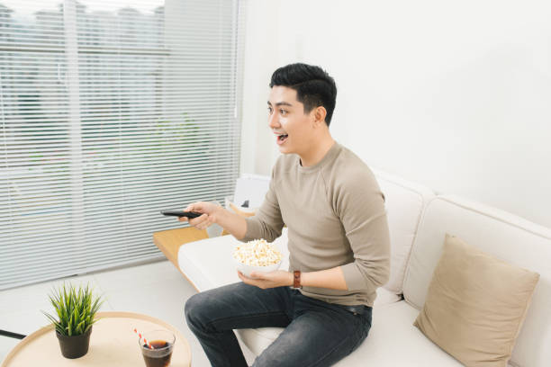 istock Young handsome man watching TV on the couch at home 879652030