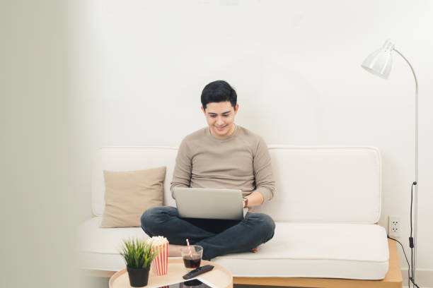 istock Freelance man working on laptop computer while spending his time at home by sitting on sofa 879655082