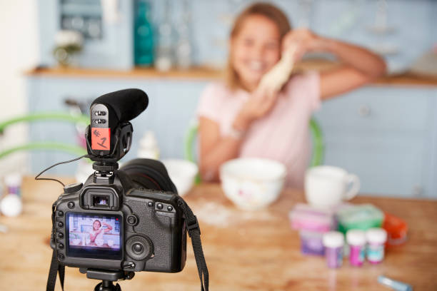 istock Young girl video blogging in kitchen seen through camera 879657704