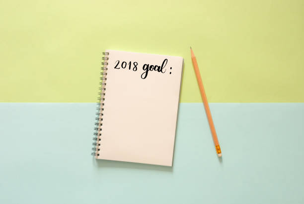 istock Minimal work space - Creative flat lay photo of workspace desk with 2018 goal list sketchbook and wooden pencil on copy space green and blue pastel background. Top view , flat lay photography. 879672258