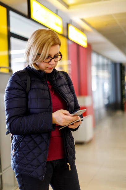 mulher usando celular enquanto aguarda um voo - global business passport transportation italy - fotografias e filmes do acervo