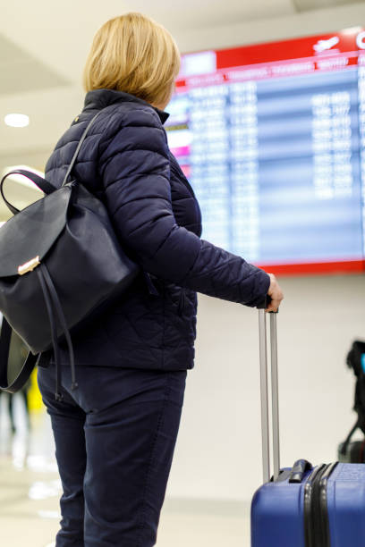 istock Woman looking at flight information screen in airport 879686206