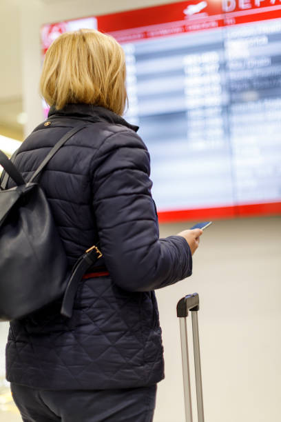 istock Woman looking at flight information screen in airport 879686776