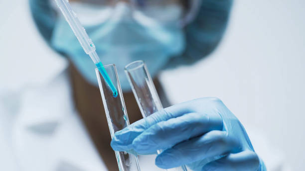 istock Medical worker adding few drops of blue liquid into test tubes, chemistry 879695622