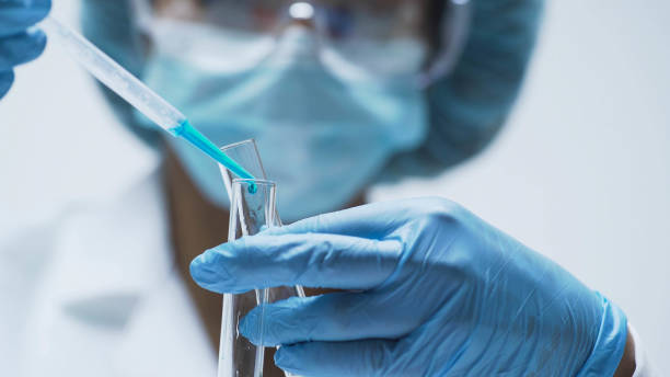 chimiste féminine ajoute les gouttes d’une substance bleue dans des éprouvettes, lab recherche - medical test people women beauty photos et images de collection