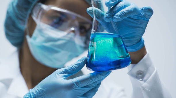 forscher beobachten chemische reaktion nach dem hinzufügen von testmaterial in flasche - chemical chemistry laboratory safety stock-fotos und bilder