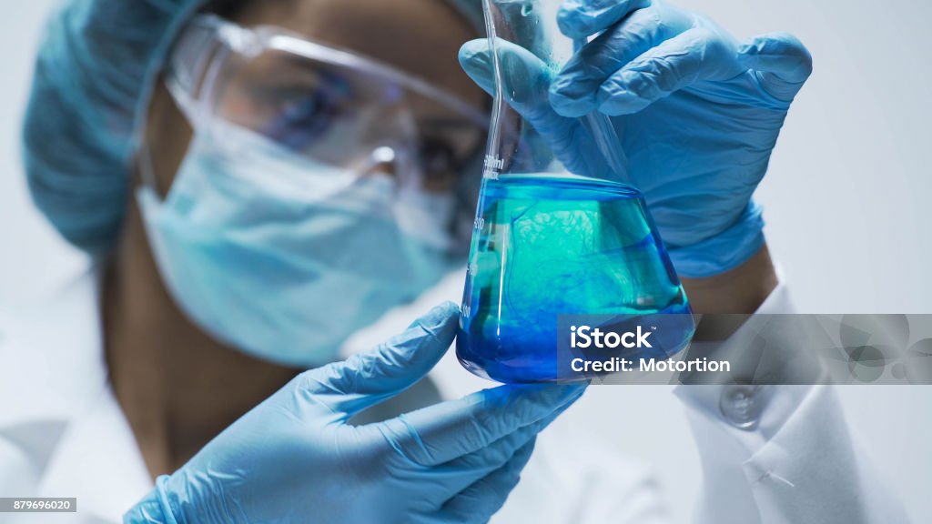 Investigador observando la reacción química después de agregar prueba material en frasco - Foto de stock de Sustancia química libre de derechos