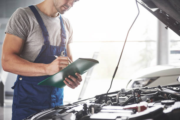 ritratto di meccanico al lavoro nel suo garage - assistenza auto, riparazione, manutenzione e concetto di persone - specialist equipment foto e immagini stock