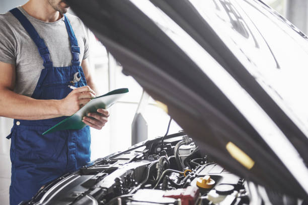 retrato de un mecánico trabajando en su garaje - de coches, reparación, mantenimiento y la gente de concepto - artificial true exam blue fotografías e imágenes de stock