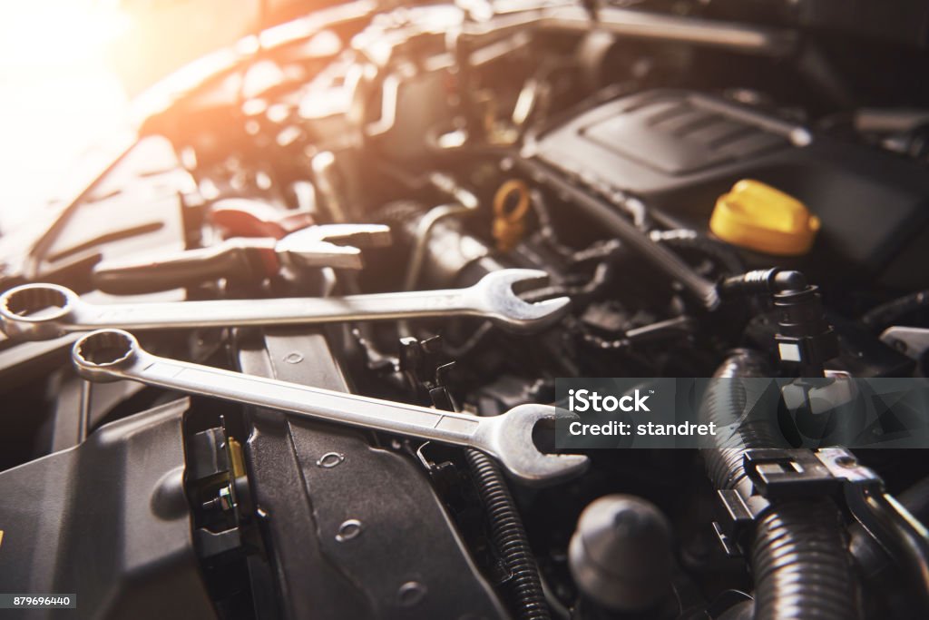 Mechanic hand checking and fixing a broken car in car service garage Mechanic hand checking and fixing a broken car in car service garage. Car Stock Photo