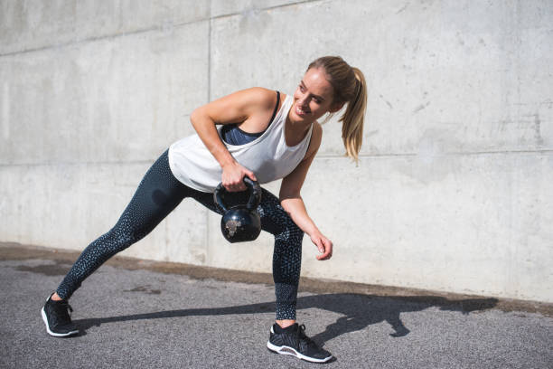 istock Woman lifting kettle bell outdoors 879708372