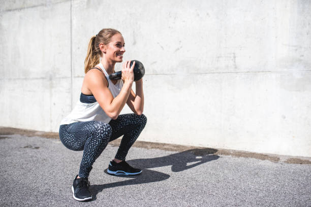 donna che fa squat con un kettlebell - kettle bell sport women muscular build foto e immagini stock