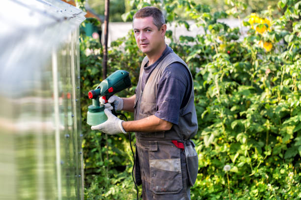 istock Positive man in overalls with spray gun in hand 879709356