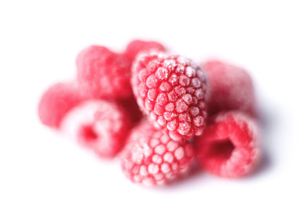 Frozen raspberry in the black plate in the center of  the pink  background. Top view. Copy space.