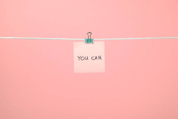 istock Pink paper sheet on the string with text You Can over colorful background 879735800
